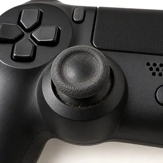 PS4 DualShock 4 controller in black, front close-up with a worn left analog stick and grime around its base