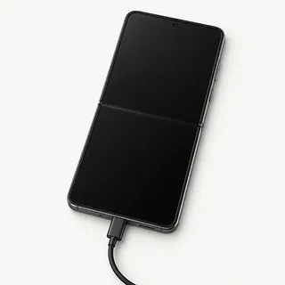 Samsung Galaxy Z Flip8 in dark gray, opened flat with a black inner screen and charging cable plugged in