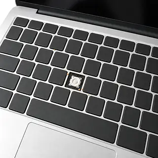 Laptop in silver, keyboard close-up with a missing keycap exposing a white mechanism and crumbs between black keys