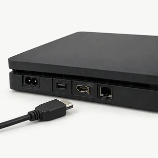 Black PS4 viewed from the back with a bent HDMI port and an unplugged HDMI cable beside it